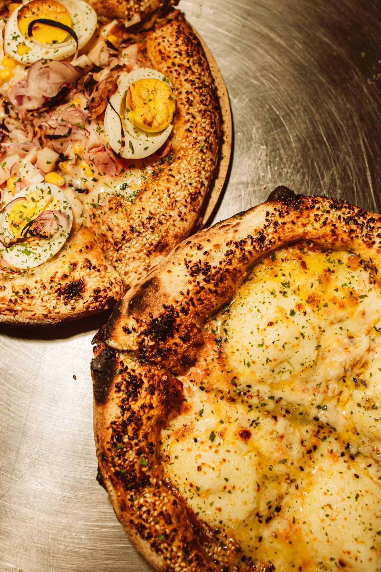 Duas pizzas da Gergelim lado a lado, com a borda coberta de gergelim tostado