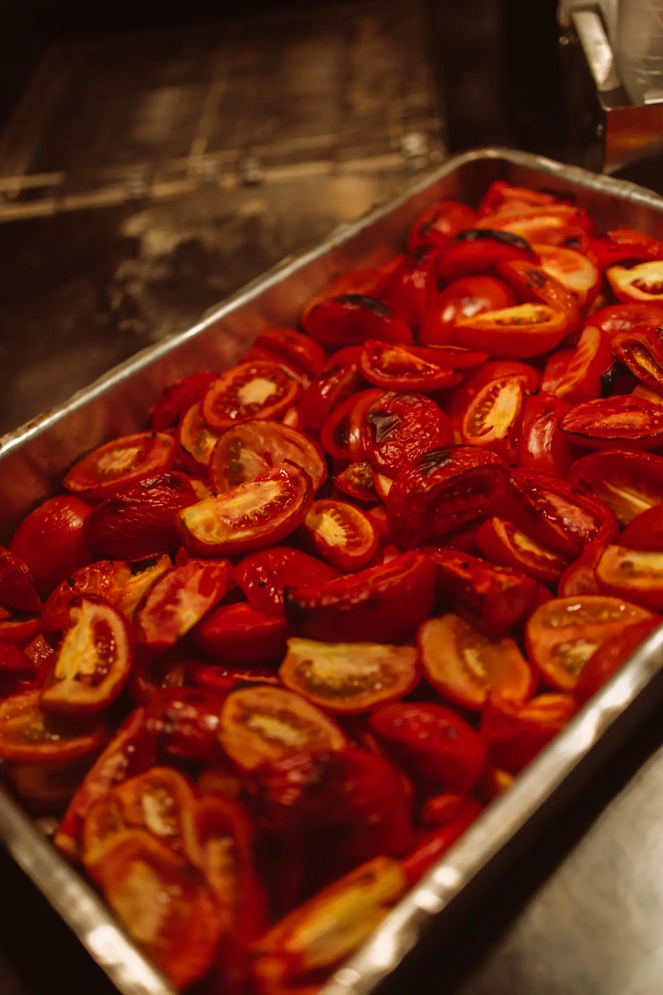 Assadeira cheia de tomates cortados e assados, com a pele tostada